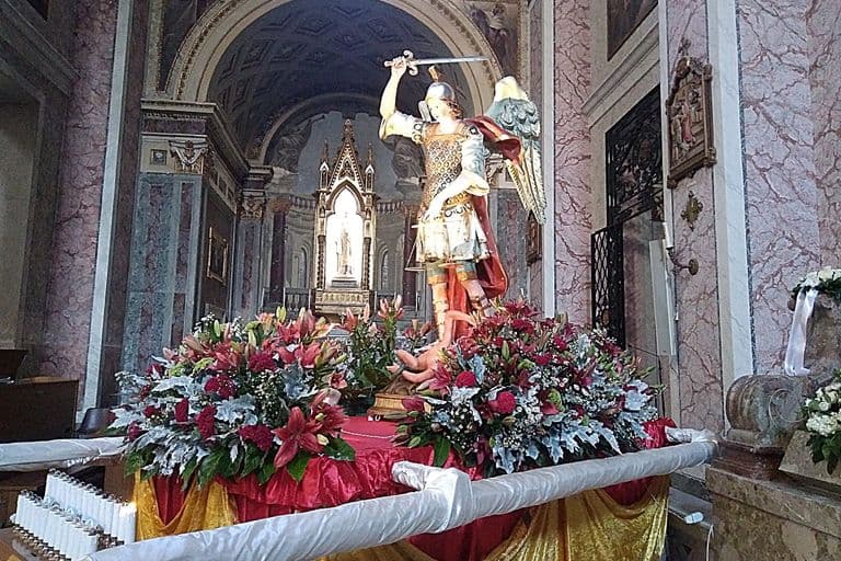 Il simulacro di San Michele sulla base processionale ornata di fiori rossi