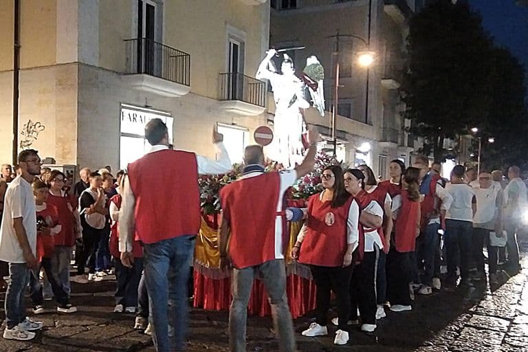 Il simulacro di San Michele portato a spalla dai portatori in casacca rossa