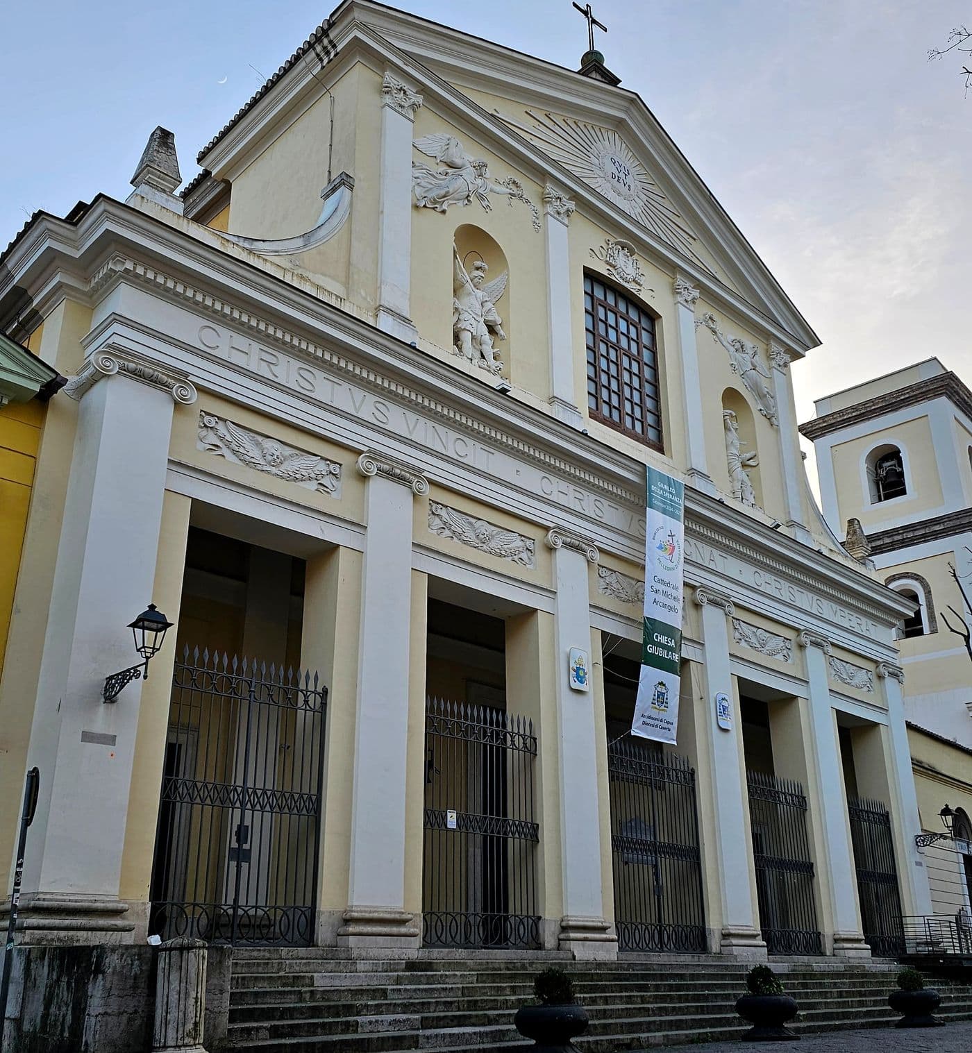 La facciata neoclassica della Cattedrale di Caserta, con il pronao a colonne, l’iscrizione CHRISTVS VINCIT e la statua di San Michele Arcangelo nella nicchia